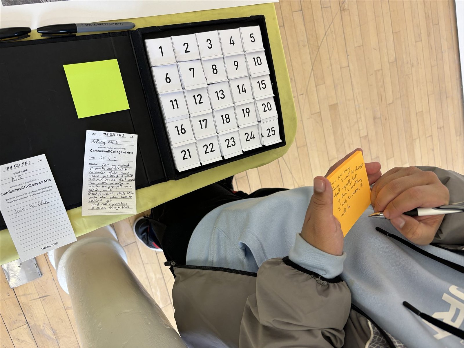 A visitor writing a response note beside the opened Moral Compass box